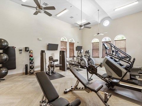 a gym with weights and other exercise equipment in a room with windows