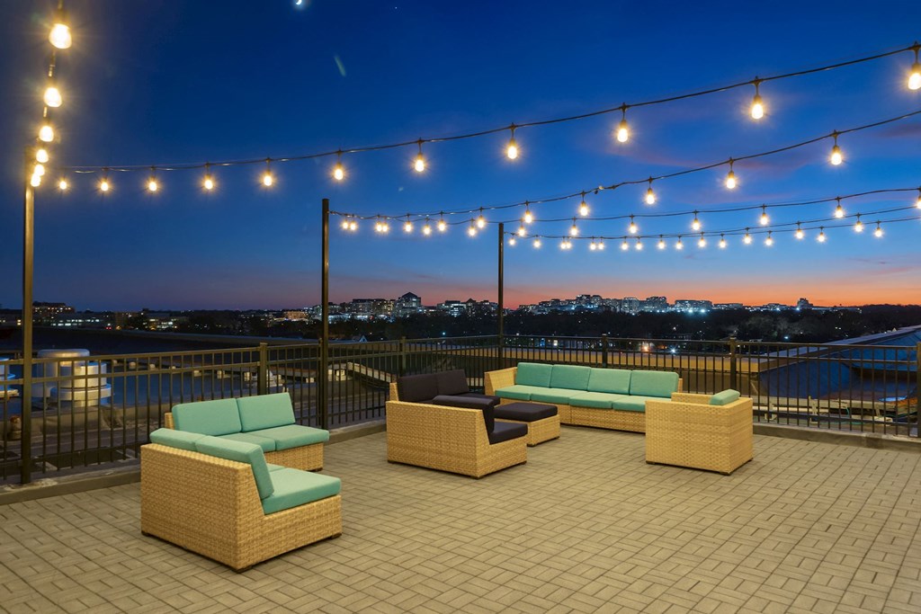 a roof deck with couches and chairs under lights