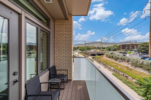 A balcony with two chairs and a table overlooking a parking lot.