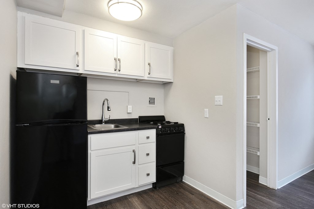 a kitchen with white cabinets and black appliances