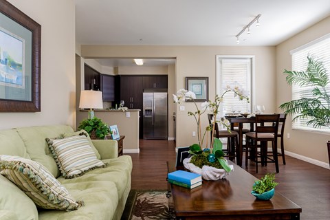 A living room with a green couch and a dining table with chairs.