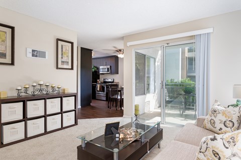 A living room with a glass coffee table and a couch with a floral pattern.