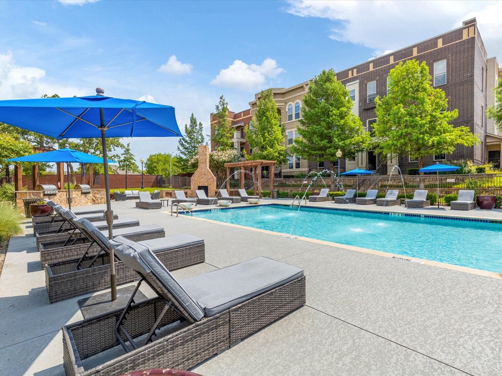 a swimming pool with lounge chairs and umbrellas in front of a building