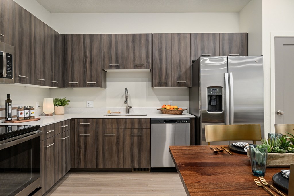A modern kitchen with dark wood cabinets and stainless steel appliances.