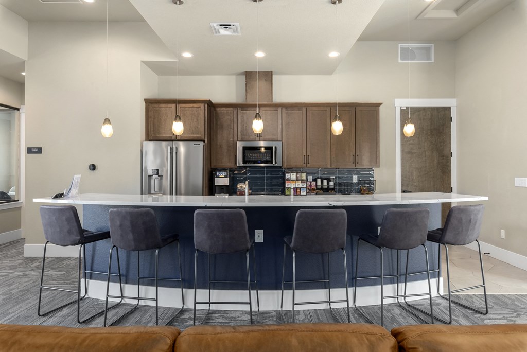 a kitchen with an island and bar with chairs and a refrigerator and