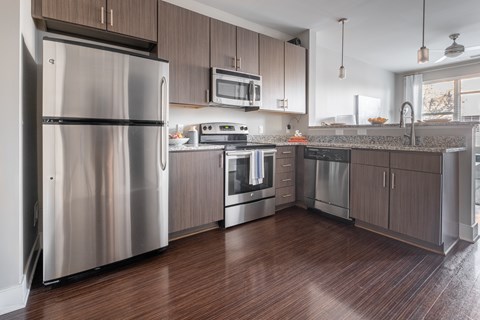 A modern kitchen with a stainless steel refrigerator and wooden cabinets.