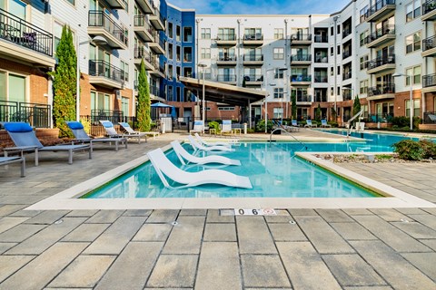 A swimming pool surrounded by lounge chairs and buildings.