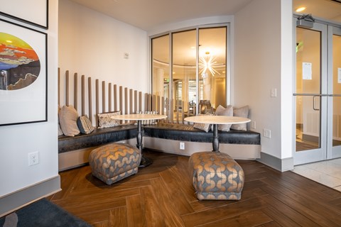 A living room with a couch, ottoman, and a painting on the wall.