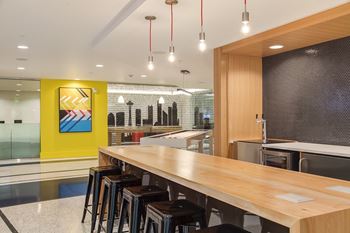 A long wooden table is surrounded by bar stools in a modern room.