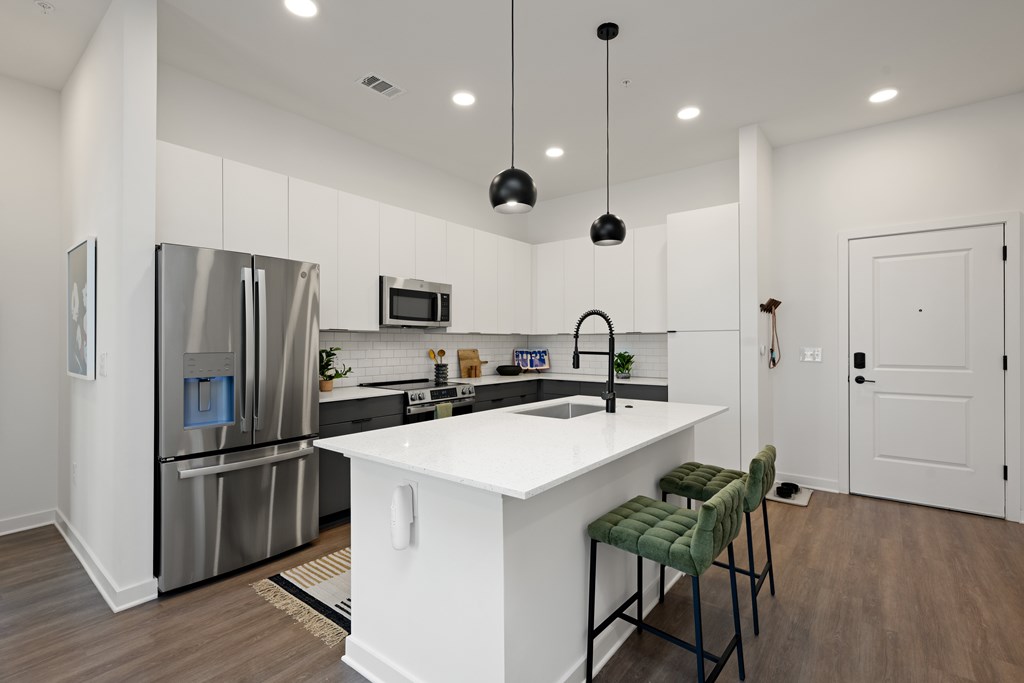 A modern kitchen with a white island and green bar stools.
