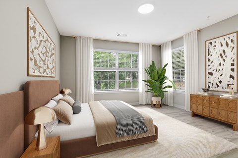 A well-lit bedroom with a large bed, a nightstand, and a dresser.