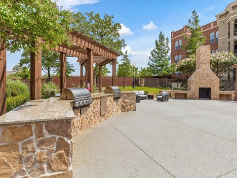 a patio with a stone fireplace and a stone wall