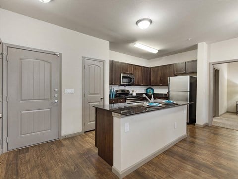a kitchen with an island and a stainless steel refrigerator