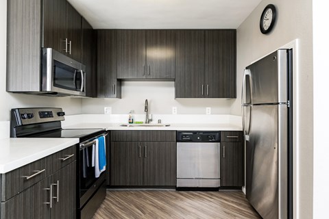 A modern kitchen with dark wood cabinets and stainless steel appliances.