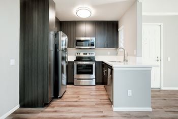 A modern kitchen with dark wood cabinets and stainless steel appliances.