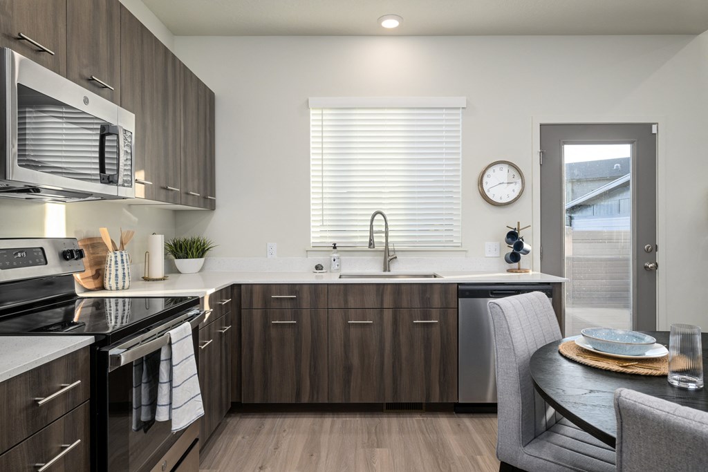 A modern kitchen with dark wood cabinets and stainless steel appliances.