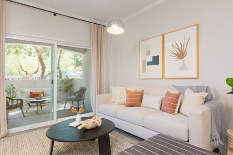 A living room with a white couch, a coffee table, and a painting on the wall.