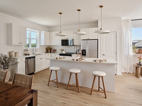 A modern kitchen with white cabinets and a wooden floor.