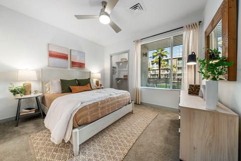 A bedroom with a bed, nightstand, and a plant on the side table at Bask Deer Valley apartment rentals in Phoenix, Arizona.