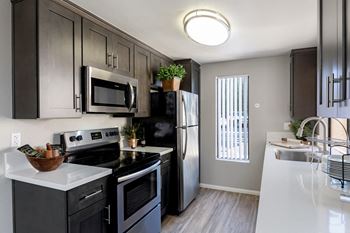 an empty kitchen with black appliances and white counter tops at The Casas Apartments, San Diego, CA
