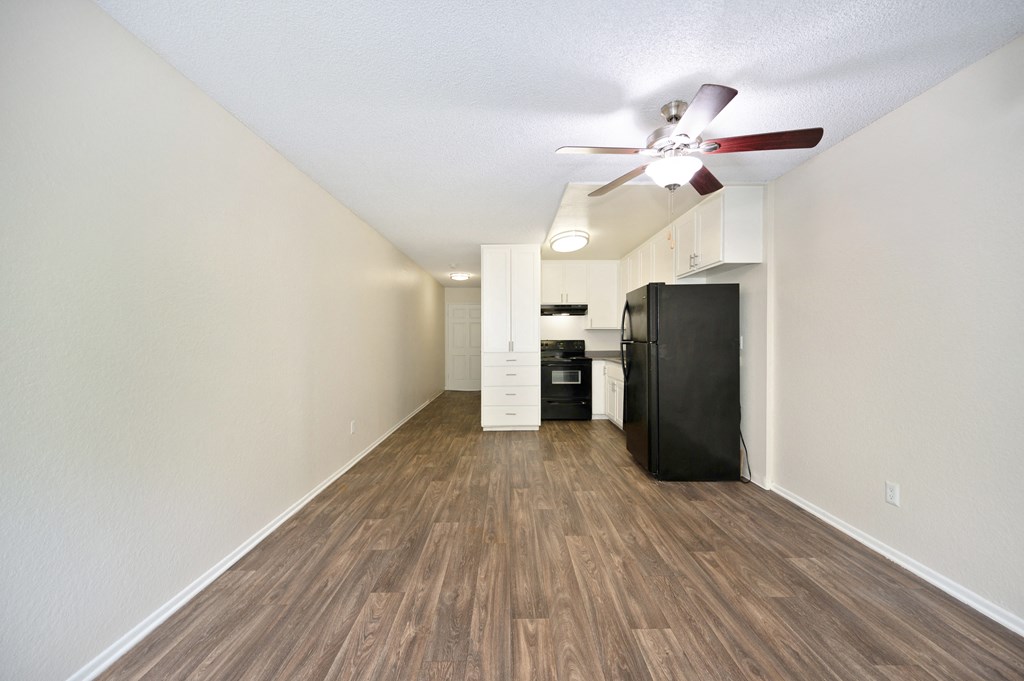 a studio apartments living space with a ceiling fan and a kitchen