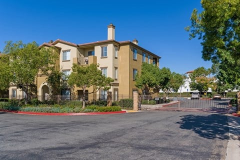 A large beige building with a red fence and gate in front.