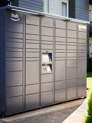 A grey Amazon Hub kiosk sits on a sidewalk.