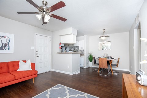 A red couch with a white pillow is in the middle of a room with a ceiling fan.