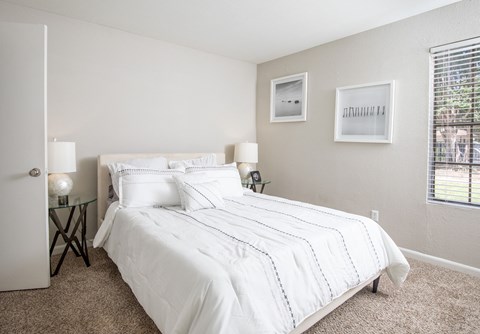 A bedroom with a large bed and two lamps.