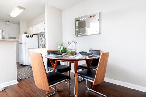 A dining table with four chairs and a mirror above it.