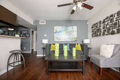A living room with a grey couch, a coffee table, and a ceiling fan.