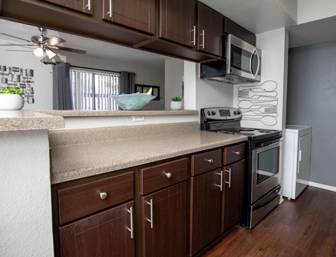 A modern kitchen with dark wood cabinets and stainless steel appliances.
