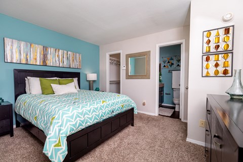 A bedroom with a bed, dresser, and mirror.