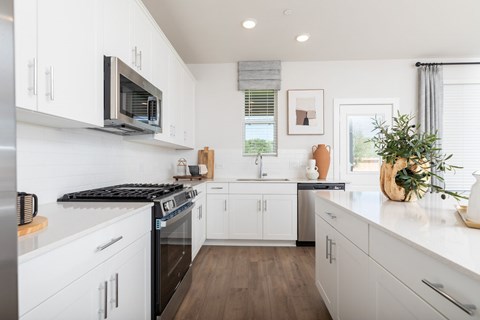 A modern kitchen with white cabinets and a black stove top.