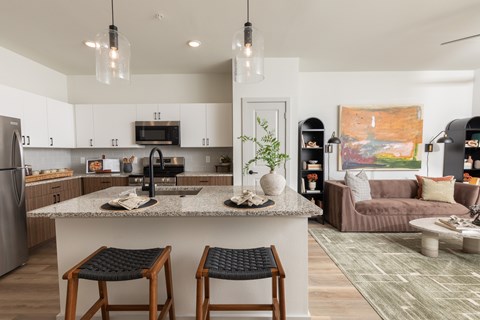 A kitchen with a bar stool in front of the island.