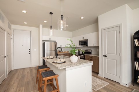 A kitchen with a white island and wooden stools.