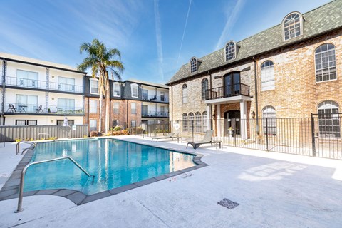 A swimming pool is surrounded by a fence and a building.