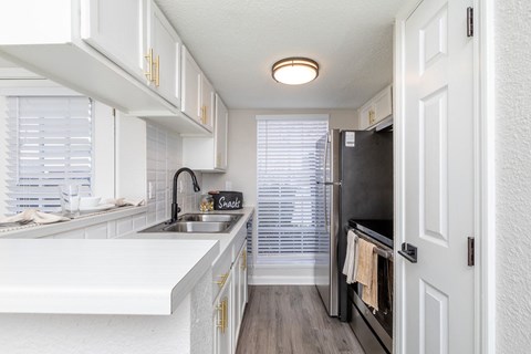 A kitchen with white cabinets and a black fridge.