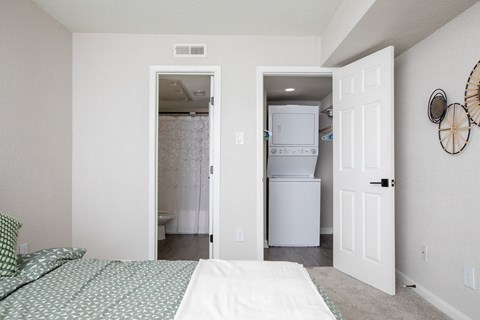 A bedroom with a bed and a refrigerator in the closet.