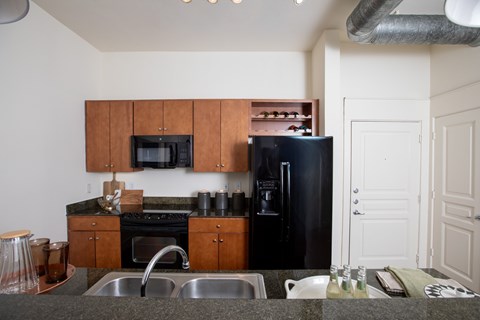 A kitchen with a black refrigerator and wooden cabinets.