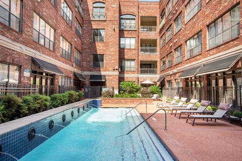 A pool surrounded by chairs and buildings.