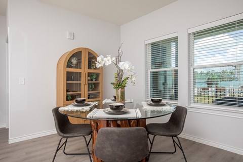 A dining room with a table set for two and a view of the outside.