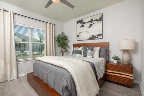 A bedroom with a bed, a ceiling fan, and a window with curtains.