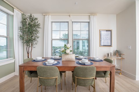 A dining room with a table set for two and a potted plant.