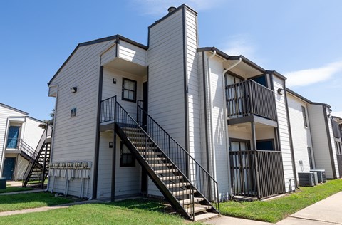 A white two-story apartment building with a black metal staircase.