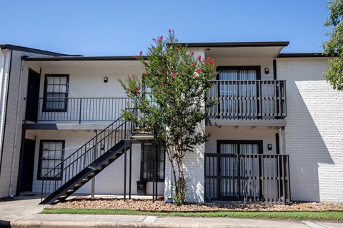 A white two-story apartment building with a black metal staircase.