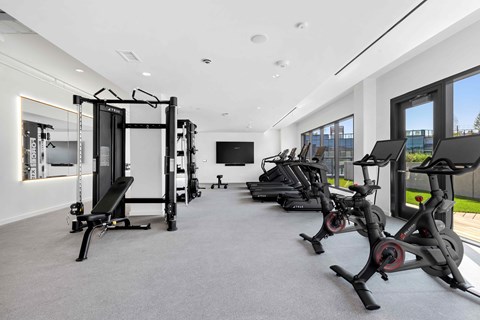 A spacious gym with a variety of equipment including treadmills, elliptical machines, and a weight rack.