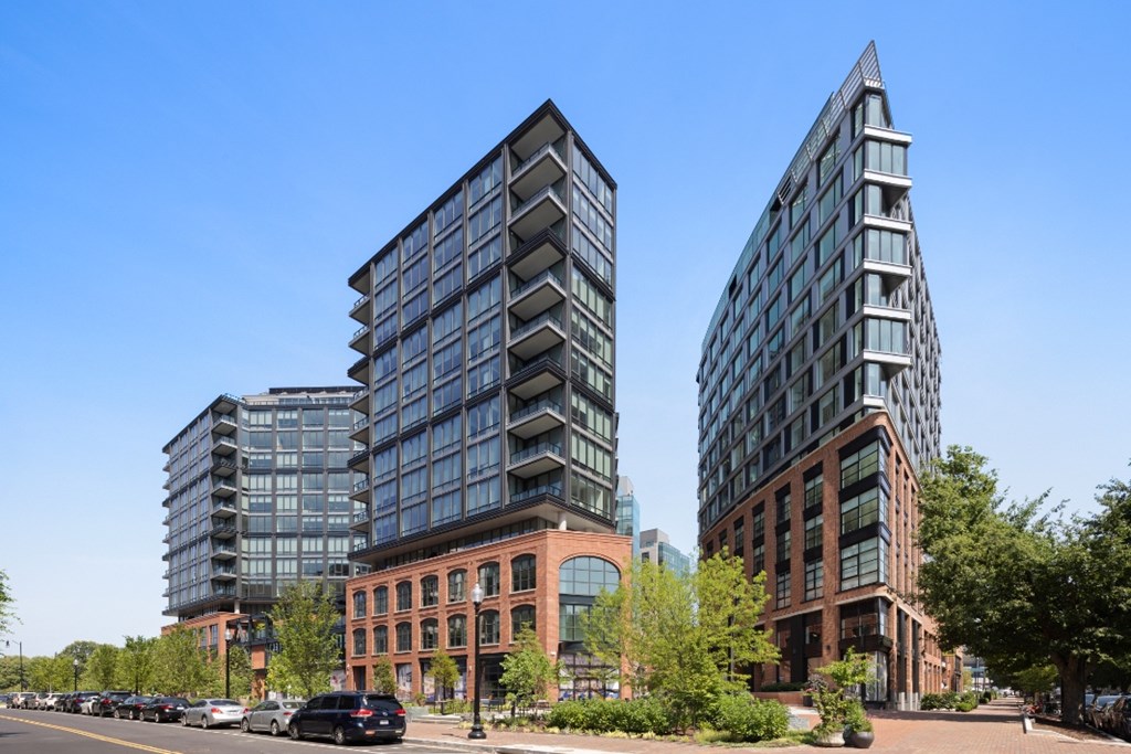 Two modern buildings stand next to each other with trees in the foreground.