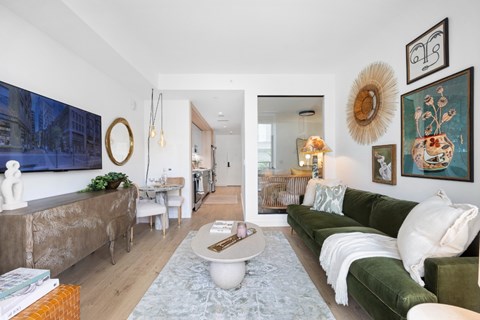 A living room with a green couch and a large painting on the wall.