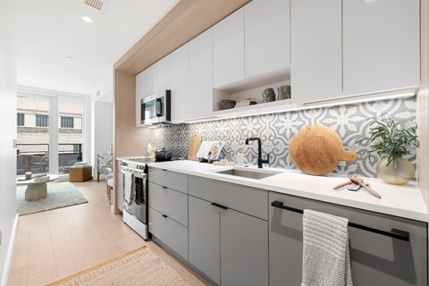 A kitchen with a white counter top and grey cabinets.